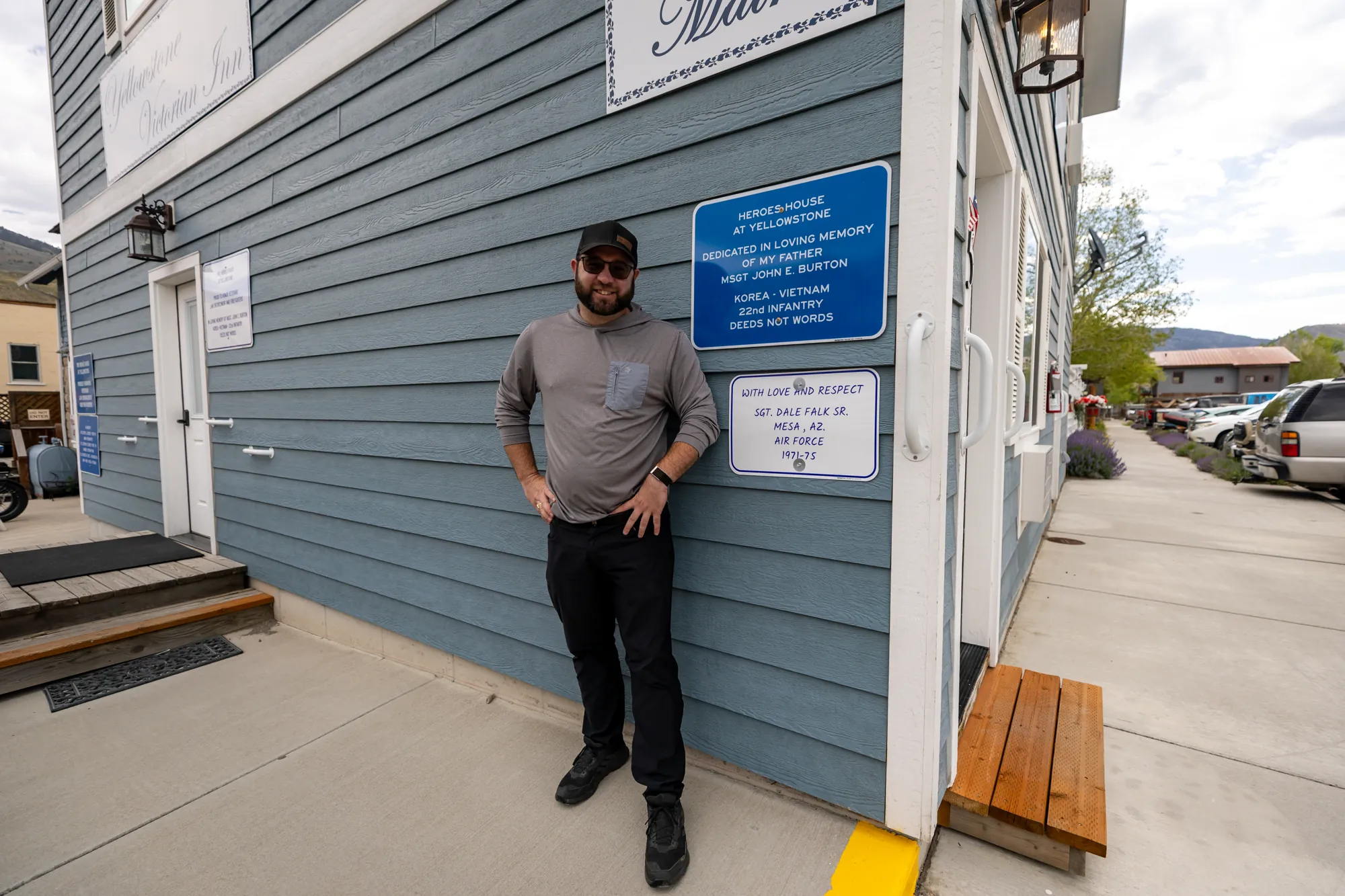 Dale Falk Jr stands beside the memorial plaque for his father, Air Force veteran Sgt. Dale Falk Sr., on the Heroes House wall